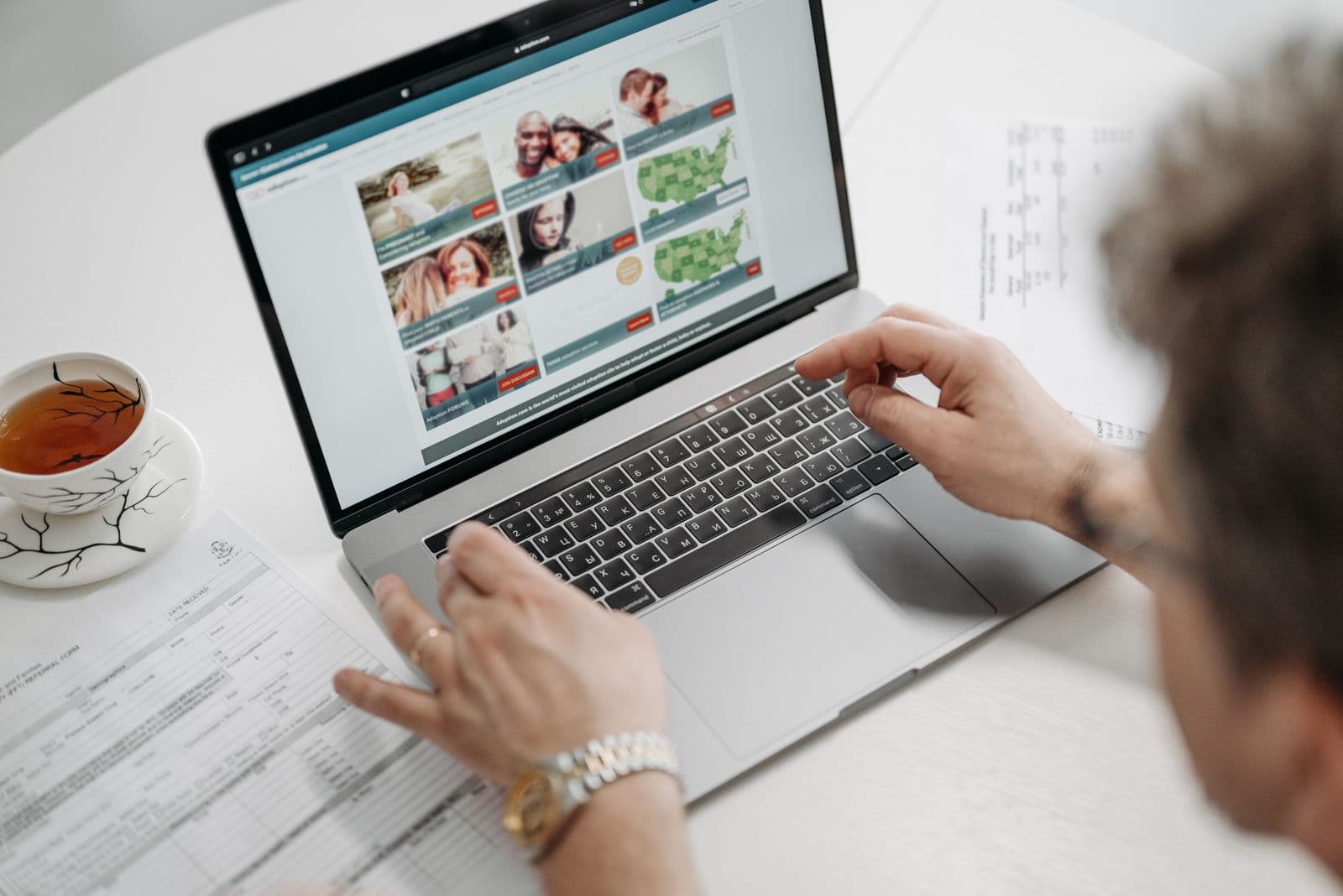Person researching on a laptop, taking notes while searching records